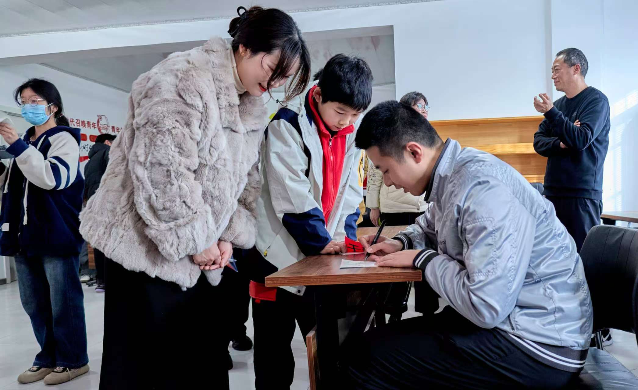i_20260223201057128834.jpg 6于新辰为在场的每一位学生和志愿者亲笔签名,送上真挚祝福.jpg
